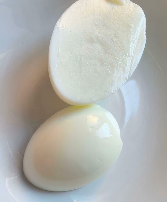 A baffling image showing two perfectly halved hard-boiled eggs with no yolks.