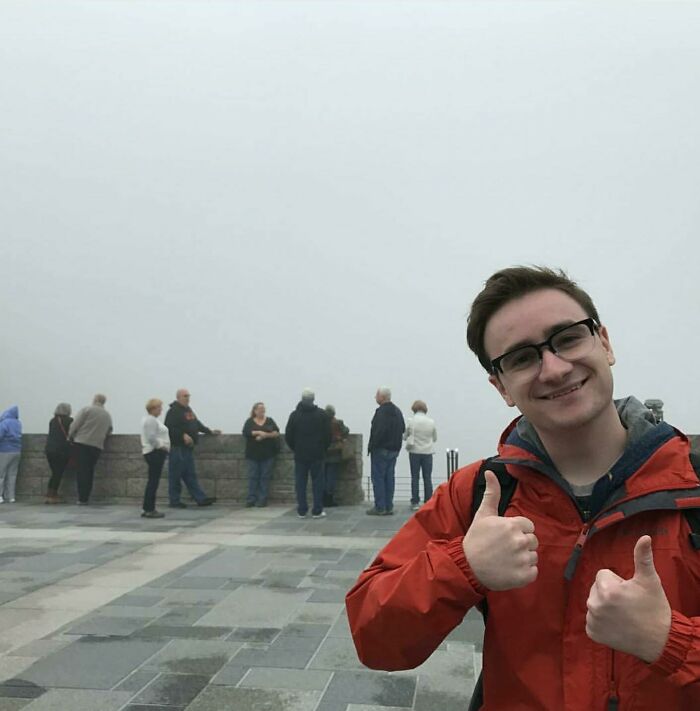 A man gives a thumbs-up while other people look at a foggy, obscured view, a trip that didn't go as planned.