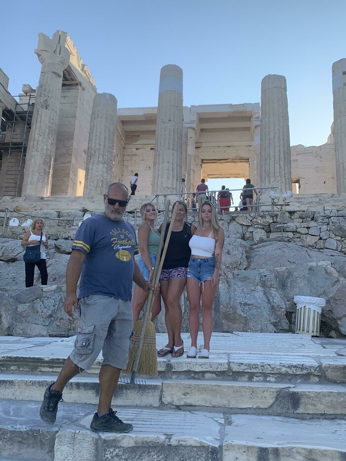 A family with a broom posing in front of ancient ruins, highlighting a trip that didnt go as planned.
