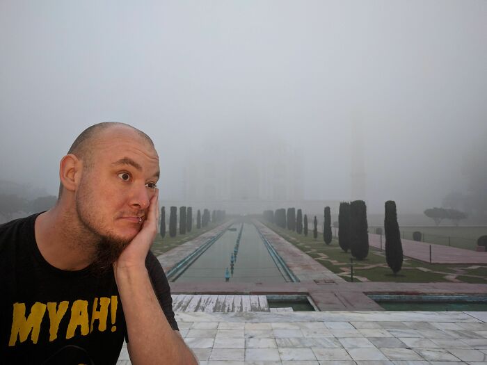 A man looking disappointed in the foreground with the Taj Mahal barely visible in heavy fog, a trip highlight gone awry.