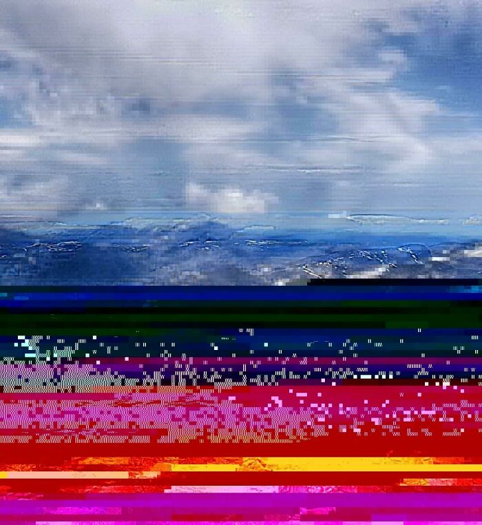 A heavily glitched digital image of a mountain landscape, representing a trip not going exactly as planned.