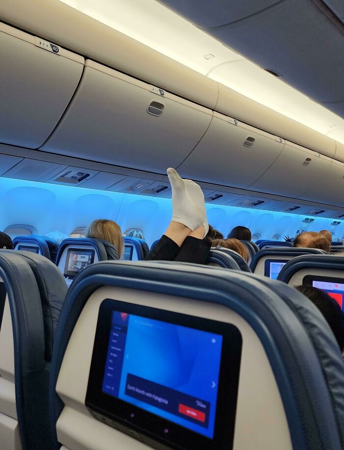 A passenger in an airplane with their feet propped up on the seat in front, highlighting an unexpected moment during trips.