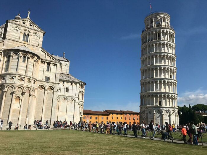 The Leaning Tower of Pisa and its cathedral stand tall, but a long line of tourists suggests a trip with delays.