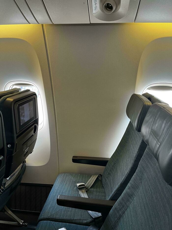 An airplane seat view, with a window seat but the window is blocked, an unexpected trip detail.