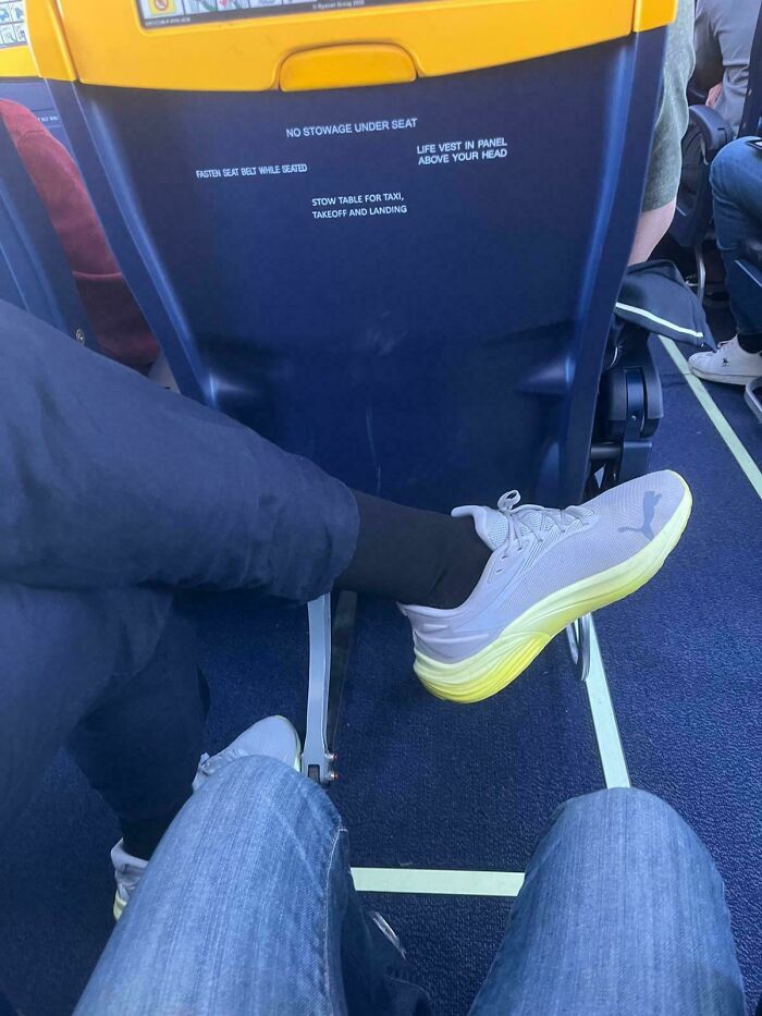 Entitled folks: Someone stretches their leg into another passenger's space on an airplane, displaying a lack of consideration.