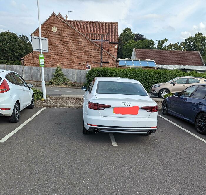 An Audi car parked poorly, taking up two spaces, showing entitled folks parking.