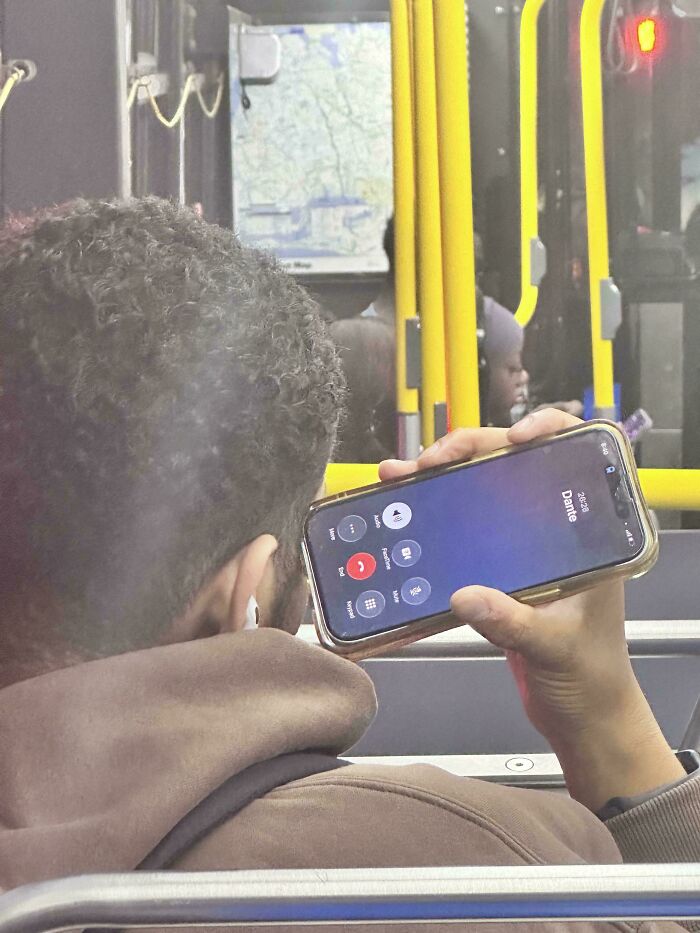 An entitled person on a bus holds a phone horizontally, with the call screen showing "Dante" and options.