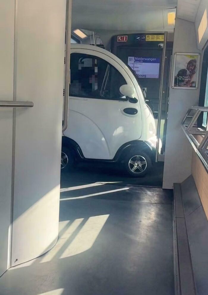 An entitled white microcar parked inside a train, an example of entitled folks taking up public space.