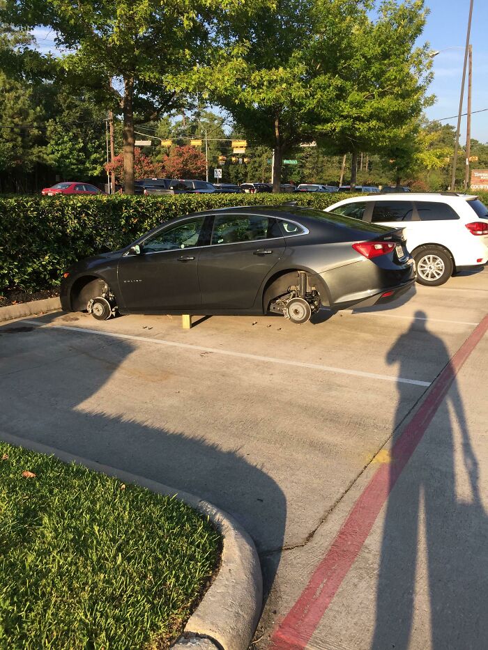 A car without wheels, resting on blocks in a parking lot, highlighting unexpected trip mishaps.