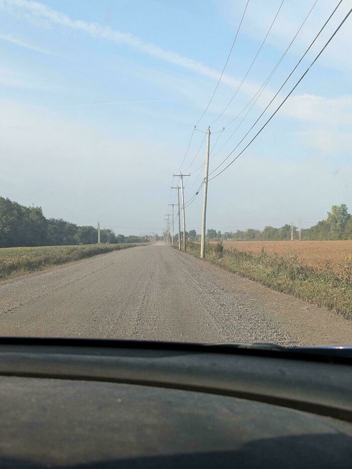 View from a car windshield of a long, straight gravel road with power lines, representing trips gone awry.