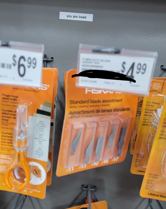 A store shelf displaying craft supplies with a small label that reads 'you are loved,' a wholesome image.