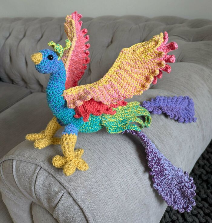Vibrant crochet bird with colorful wings on a couch