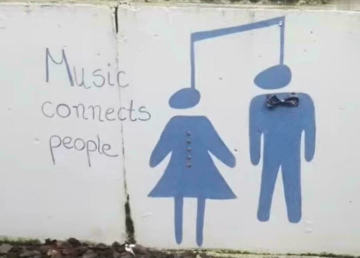 A humorous design fail of a wall drawing showing two stick figures with musical notes for heads and the text Music connects people.