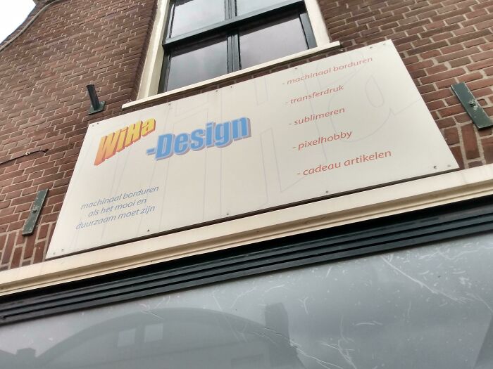 A sign for Witte Design on a brick building, an example of design fails due to poor contrast and legibility.