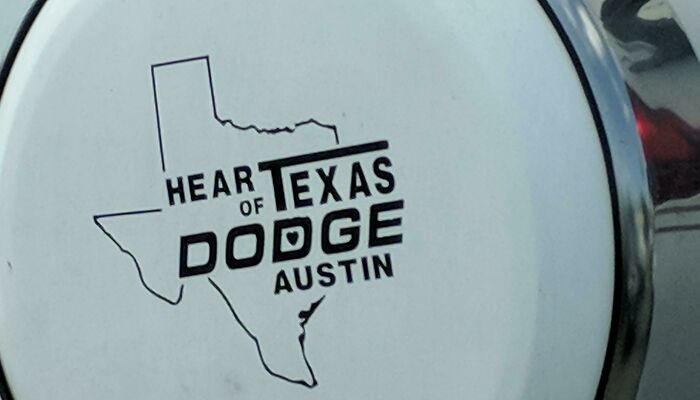 A poorly designed logo with the words Hear of Texas Dodge Austin inside an outline of the state of Texas, showcasing design fails.