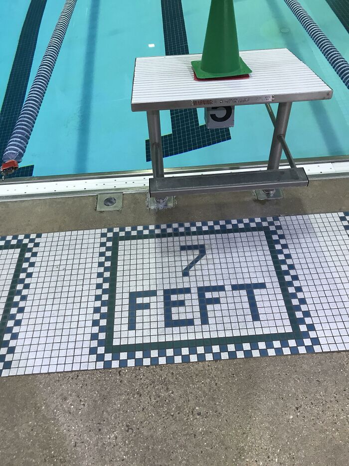 A swimming pool deck with 7 FEET written in tiles where the water is only 5 feet deep, a clear design fail.