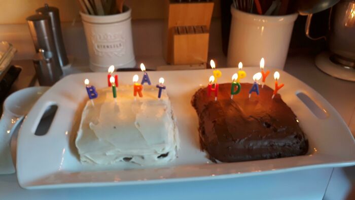 Two birthday cakes with candles spelling out HAPPY BIRTHDAY, a design fail with candles unevenly spaced.