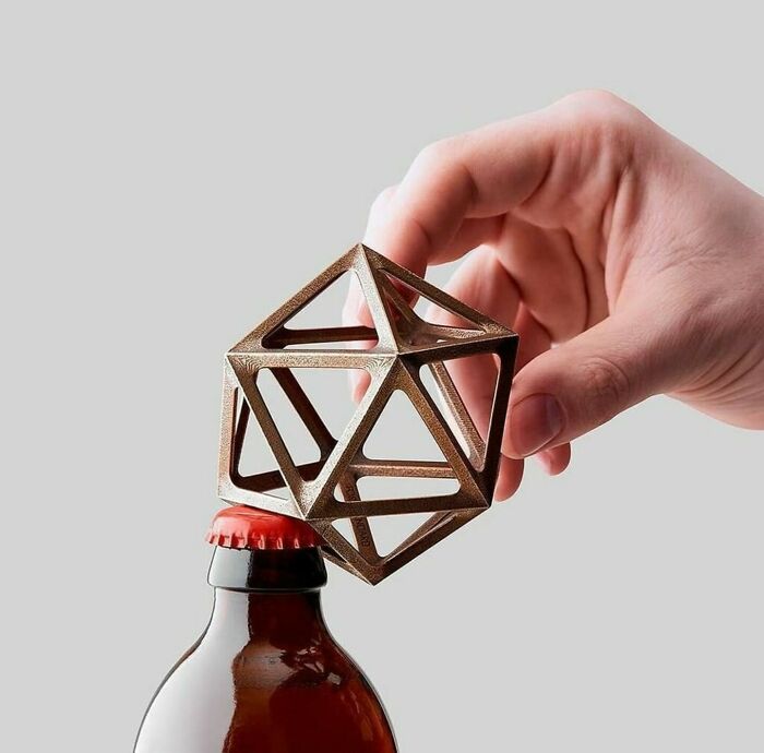 Hand holding a geometric bottle opener over a beer bottle, an impressive example of design fails.