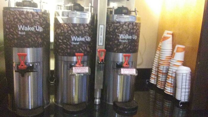 Three coffee dispensers labeled Wake Up Bold, Decaf, and Regular, with mismatched warning signs, highlighting design fails.