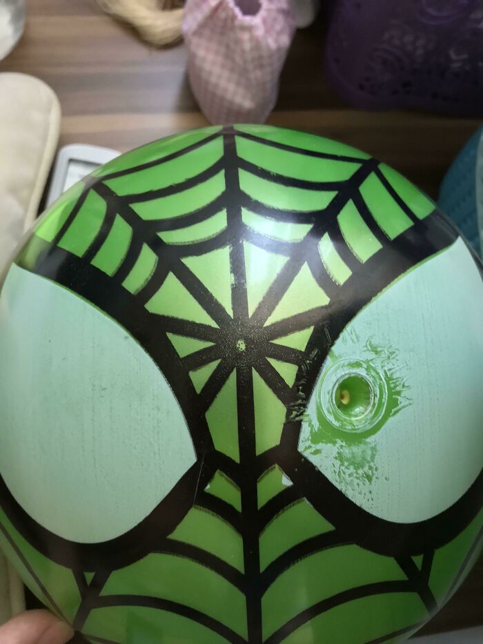 A close-up of a green Spider-Man themed ball with the inflation nozzle awkwardly placed on an eye, a clear design fail.