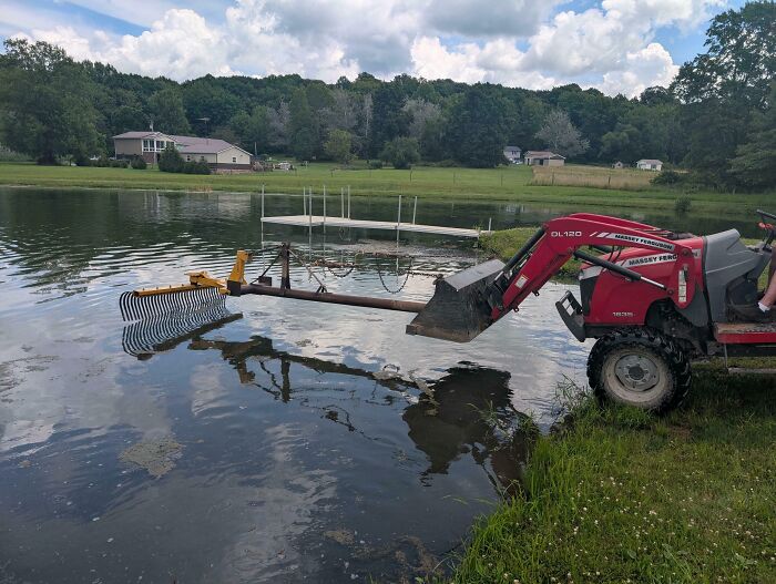 A tractor with a rake attachment, cleaning a pond, an example of people turning random junk into clever solutions.