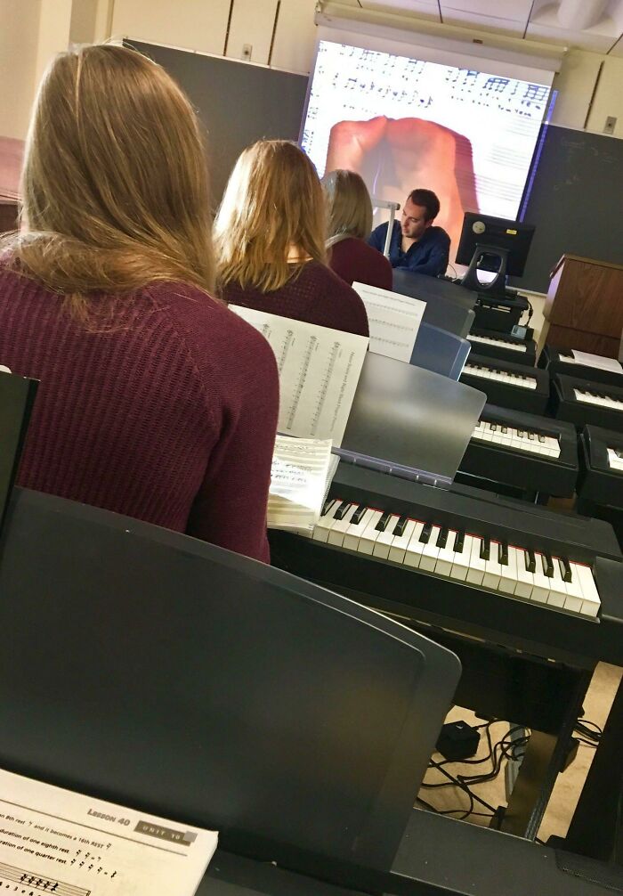 Students in a music class with keyboards, a weird and unexpected moment projected on a screen.