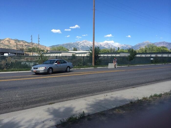 A hilariously bad DIY example of a man sitting on a large slab by the side of the road.
