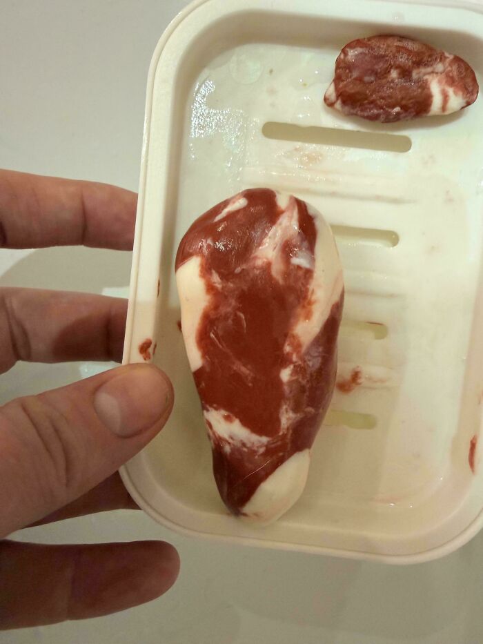 A hand holds a soap dish with a weird red and white marbled soap, making the day more interesting.