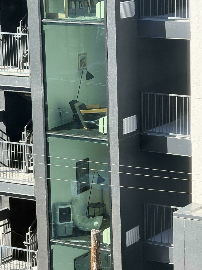 A tall building with multiple floors visible through large windows, showing office interiors. An interesting moment of modern architecture.