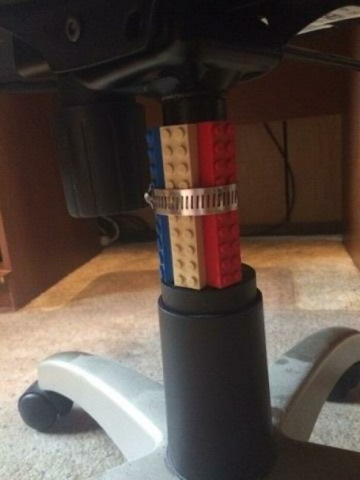 A DIY office chair repair using colorful toy bricks and a metal clamp to stabilize the seat.
