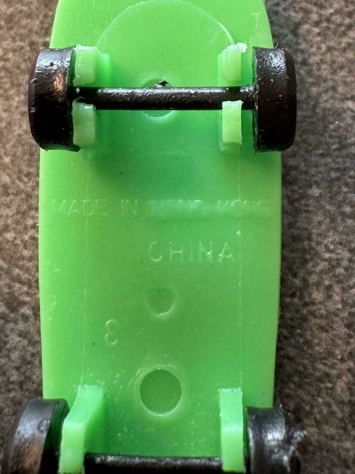 The underside of a green toy skateboard showing manufacturing marks 'MADE IN HONG KONG' and 'CHINA', highlighting an unexpected detail.