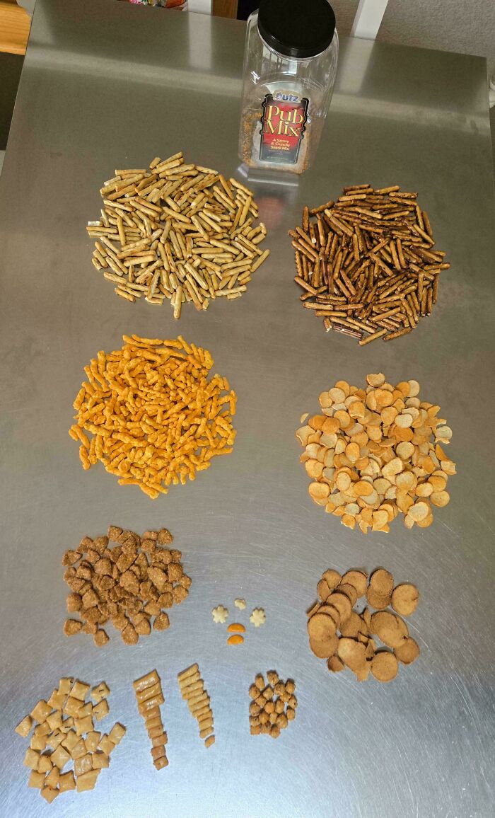 An array of different snack mixes laid out on a metal table, separated into piles. A weird moment for snacks.