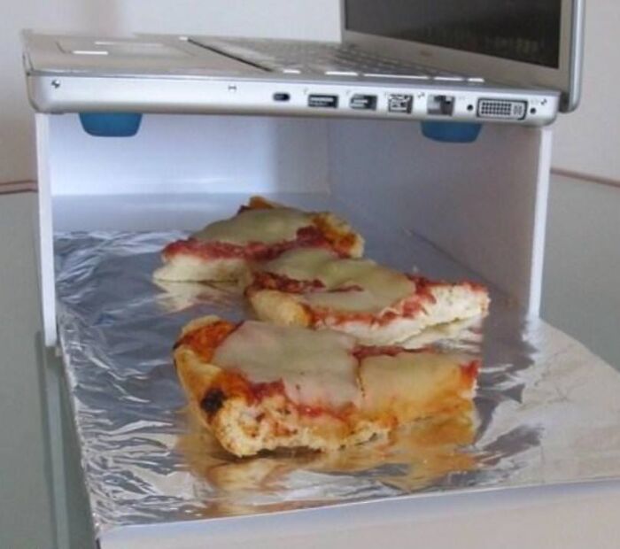 A hilariously bad DIY example: a laptop used as a pizza warmer, with slices of pizza underneath it.