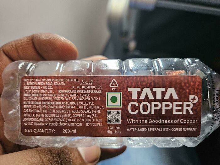 A hand holding a clear plastic bottle of Tata Copper with nutritional info. An unexpected moment captured.