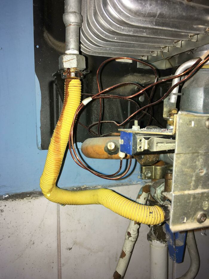 A DIY gas pipe connection with a yellow corrugated hose and exposed wires, revealing a hazardous setup.