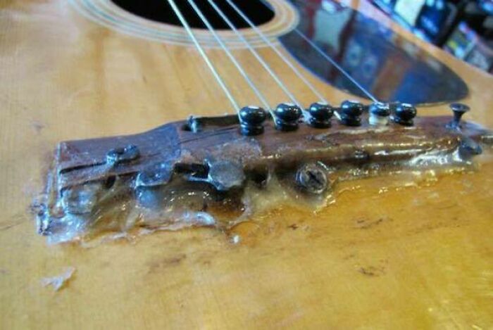 Close-up of a DIY guitar bridge poorly reattached with excessive, dried glue, showing a bad repair.