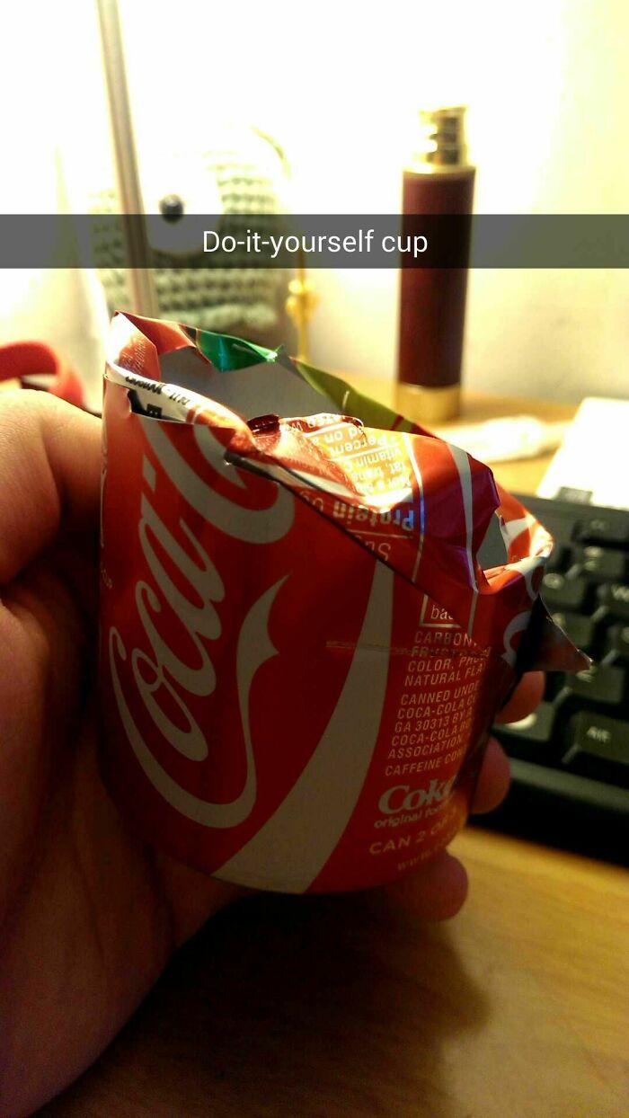 A hand holding a hilariously bad example of DIY craftsmanship: a cup made from a crushed soda can.