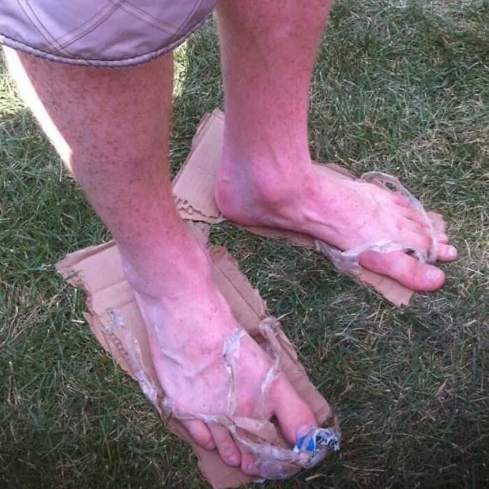 A person wearing hilariously bad DIY sandals made from cardboard and plastic bags.