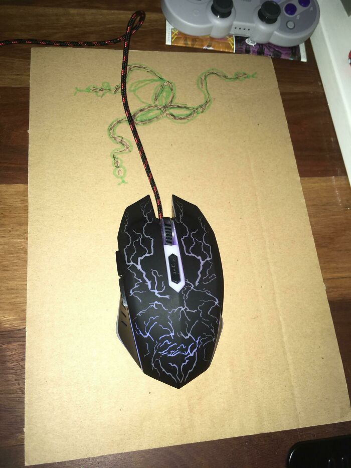 A computer mouse on a piece of cardboard with a drawn mouse pad, showcasing a hilariously bad example of DIY.