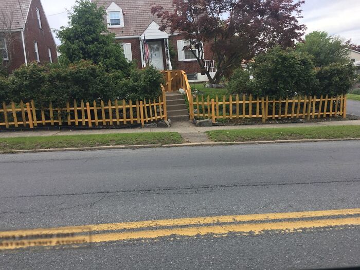 Hilariously bad DIY fence in front of a house, leaving a gap where a pathway should be.