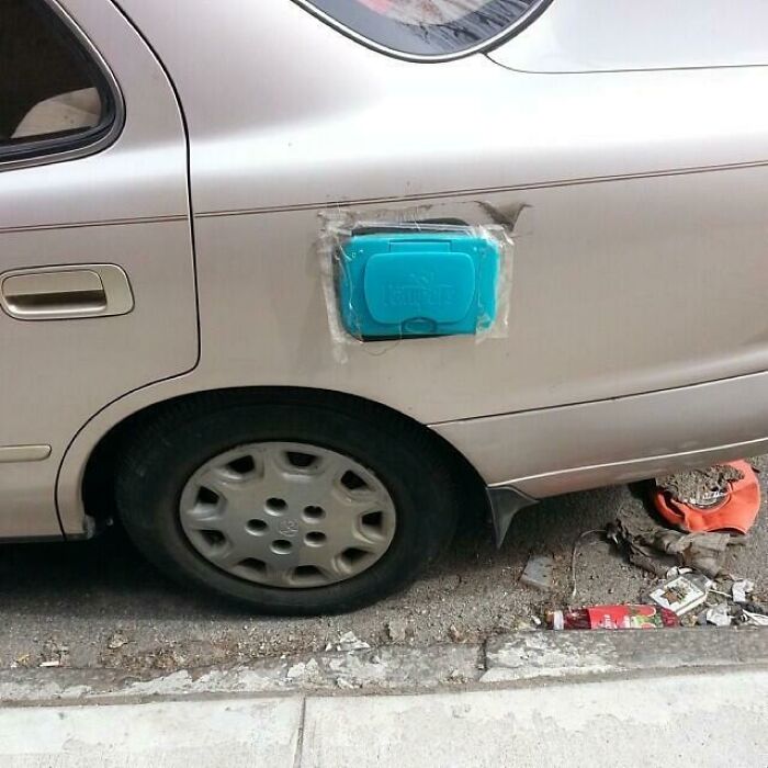 Hilariously bad DIY car repair with a wet wipe container taped over the gas cap opening.