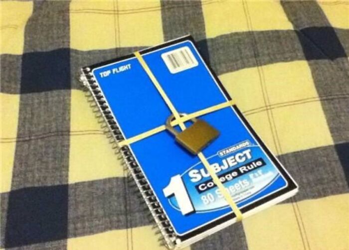 Hilariously bad DIY security for a school notebook, locked with rubber bands and a tiny padlock.