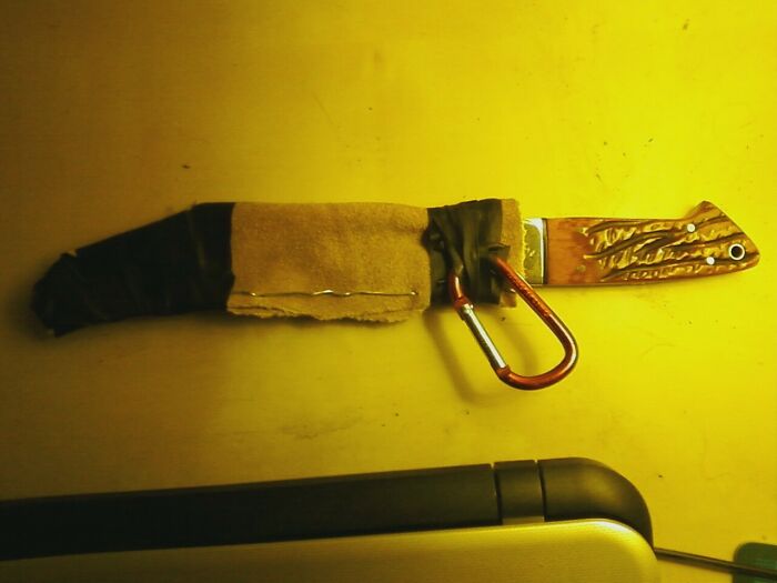 A knife with a fabric and tape sheath, attached to a carabiner, a hilariously bad example of DIY