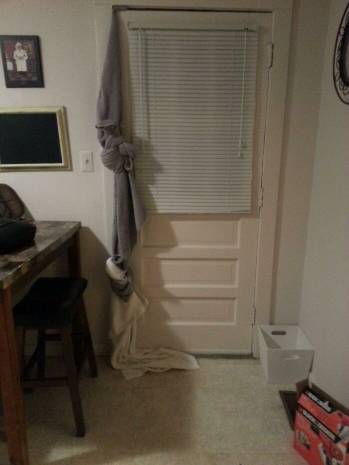 A door with a blanket tied around it, hanging over the blinds, a hilariously bad example of DIY