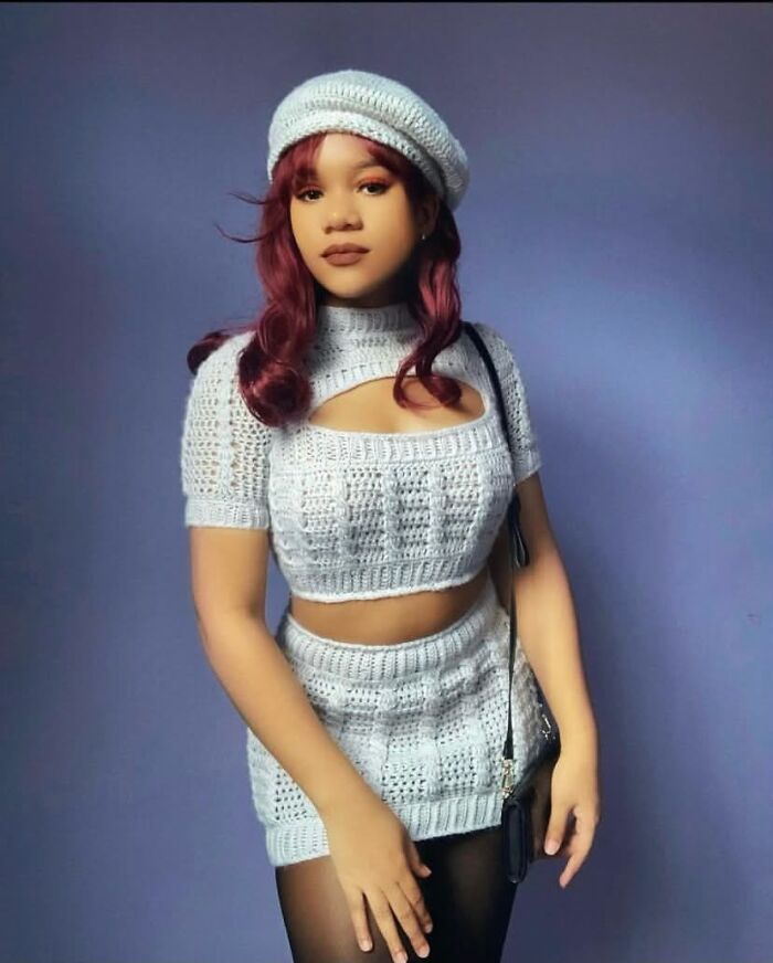 A young woman in a knitted outfit with red hair, showcasing her unique style and incredible accomplishments.