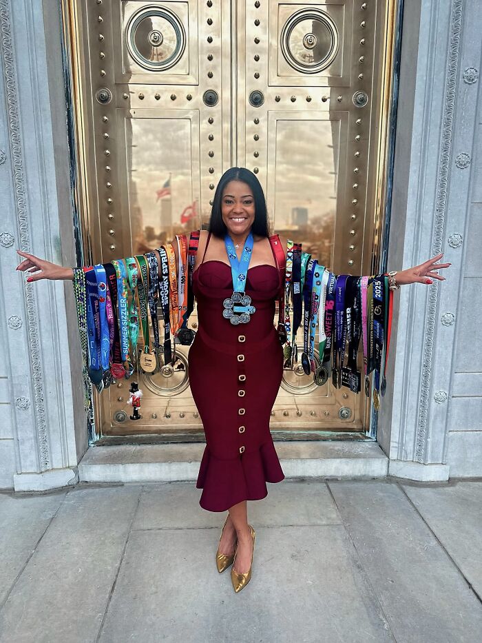 A woman wearing a dress and many race medals, proudly displaying her incredible accomplishments.