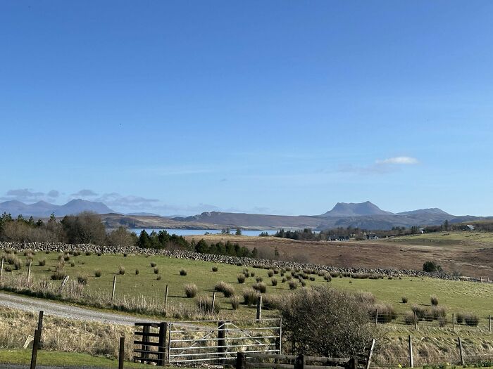 Panoramic view of a green rural landscape with mountains and a lake under a clear blue sky, an incredible accomplishment of nature.