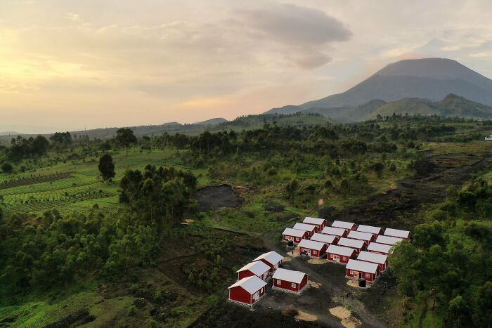 Aerial view of small red houses in a lush green valley, showcasing an incredible accomplishment in community development.