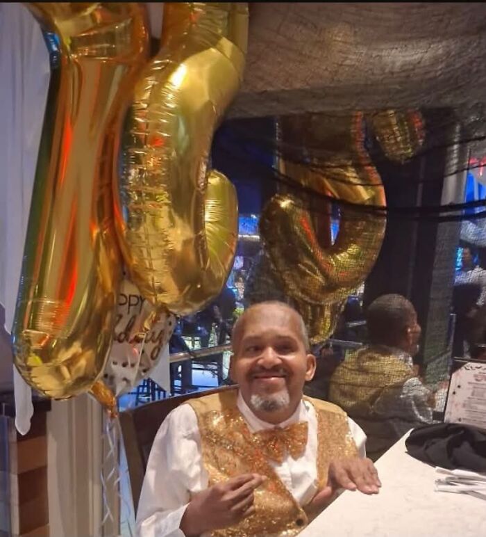 A man in a gold vest celebrating surrounded by gold balloons, showcasing an incredible accomplishment.