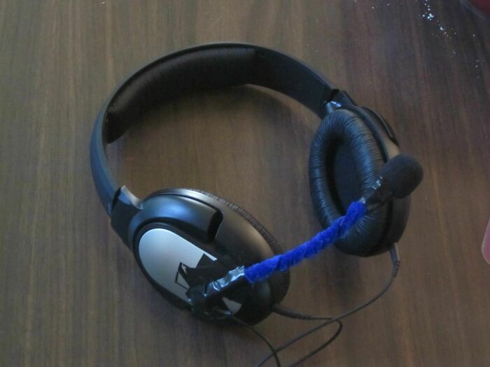 Hilariously bad DIY headphones: a microphone attached with tape and a blue pipe cleaner.